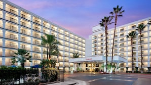 A multi-story hotel with a large entrance and palm trees.