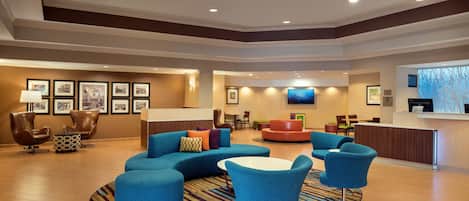 A spacious lobby with a blue sofa, armchairs, and a reception desk.