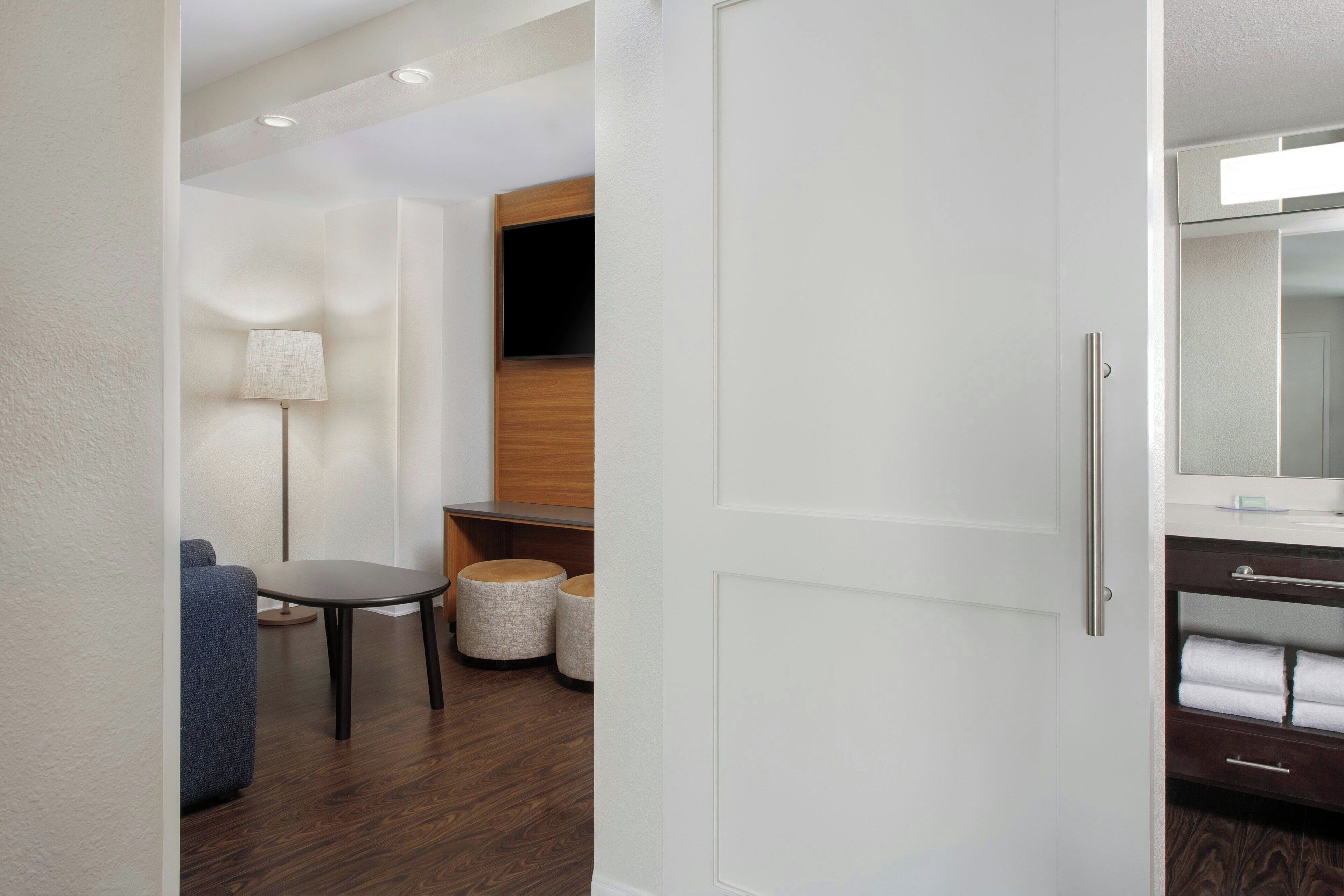 A modern bathroom with a wooden vanity, a mirror, and a towel rack.
