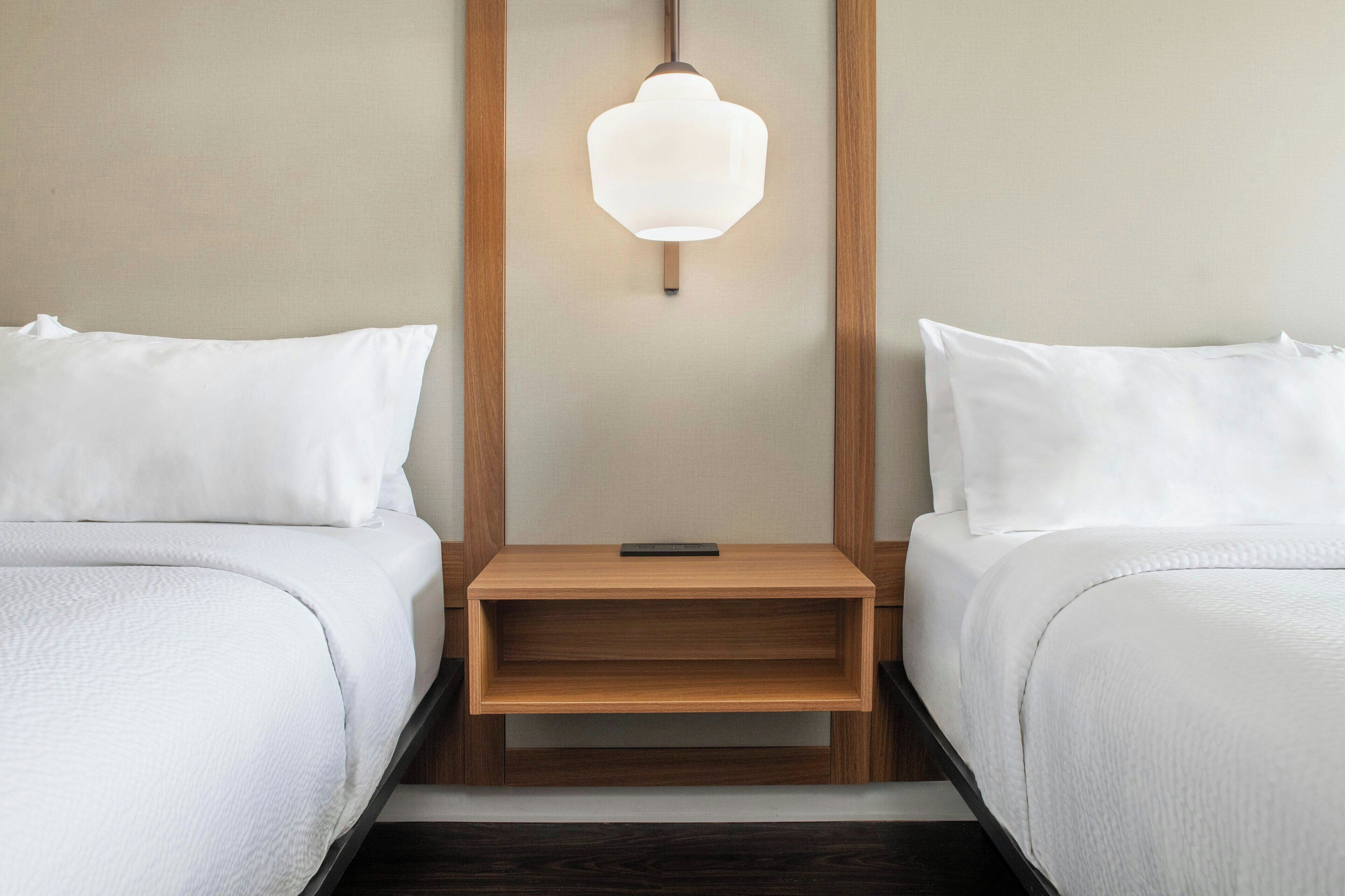 Ein Hotelzimmer mit zwei Betten, einem Nachttisch und einer Wandleuchte.