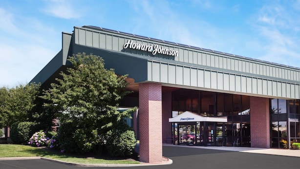 A Howard Johnson hotel with a modern facade, large windows, and a well-maintained garden area.