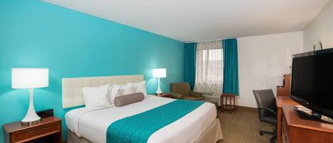 Habitación de hotel con una cama, dos mesitas de noche con lámparas, un escritorio con televisor y una silla.