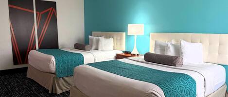 Habitación de hotel con dos camas, una pared de acento color turquesa y un diseño moderno.