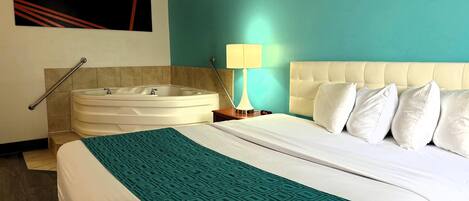 A hotel room with a large bed, a bathtub, a wall-mounted artwork, and a bedside lamp.