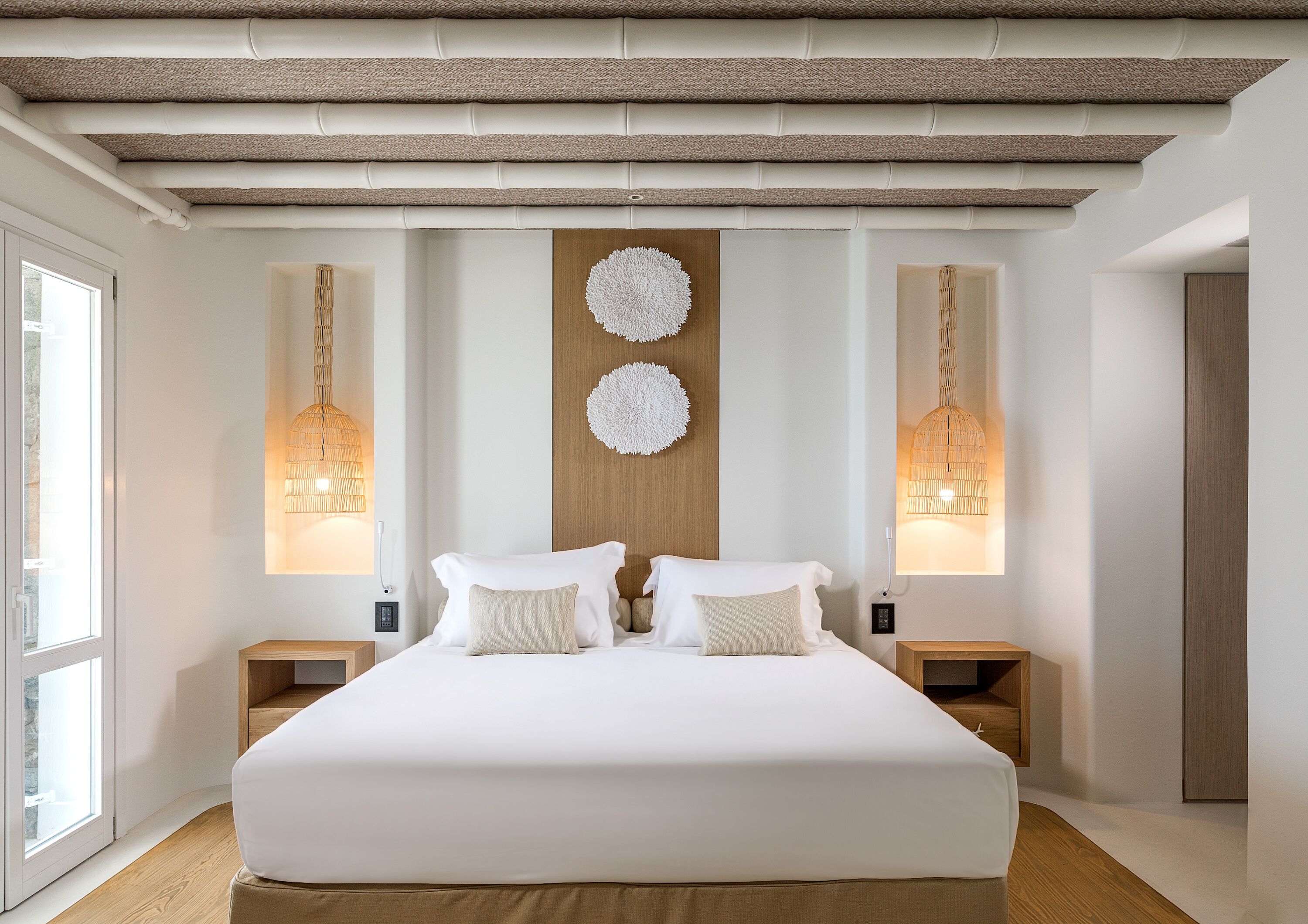 A modern bedroom with a large bed, two bedside tables, and a wooden headboard.