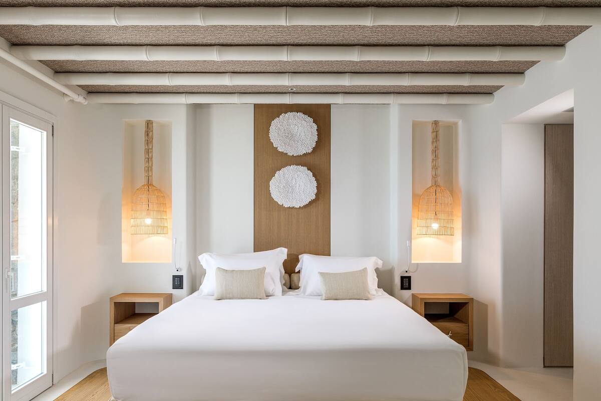 A modern bedroom with a large bed, two bedside tables, and a wooden headboard.
