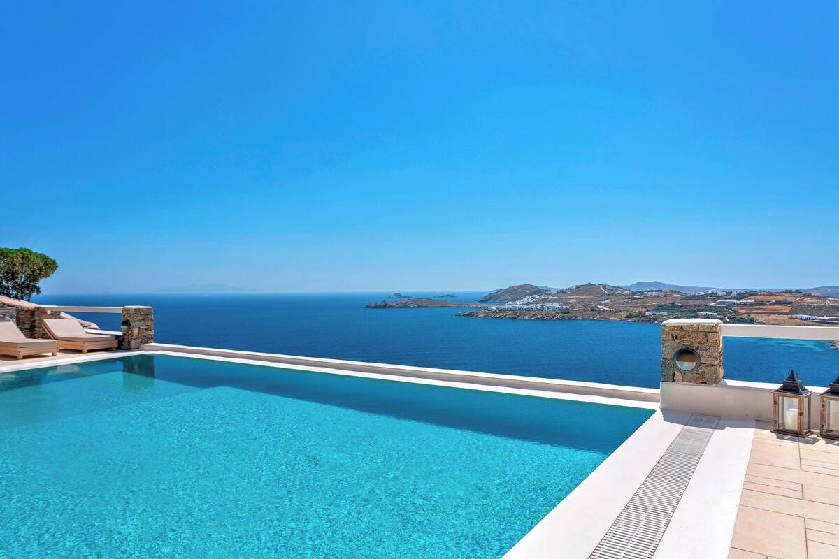 A clear blue pool with a view of the sea and distant islands.