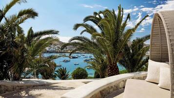 A seaside view with palm trees, a beach, and boats in the water.