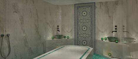 A modern bathroom with a marble bathtub, green mosaic tiles, and decorative bowls on shelves.