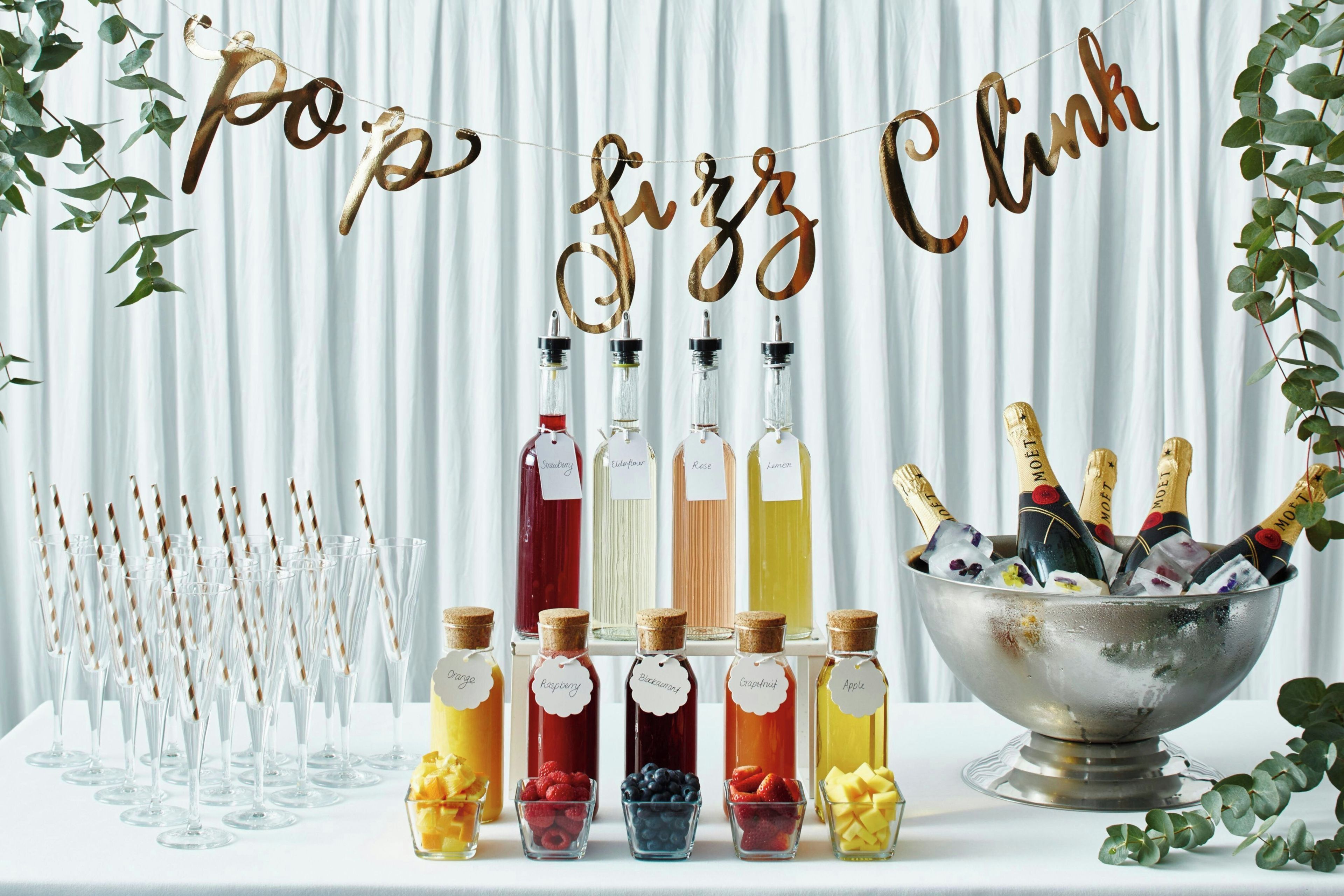 A beverage station with various drinks and a sign that reads 'Po&z fizz clink'.