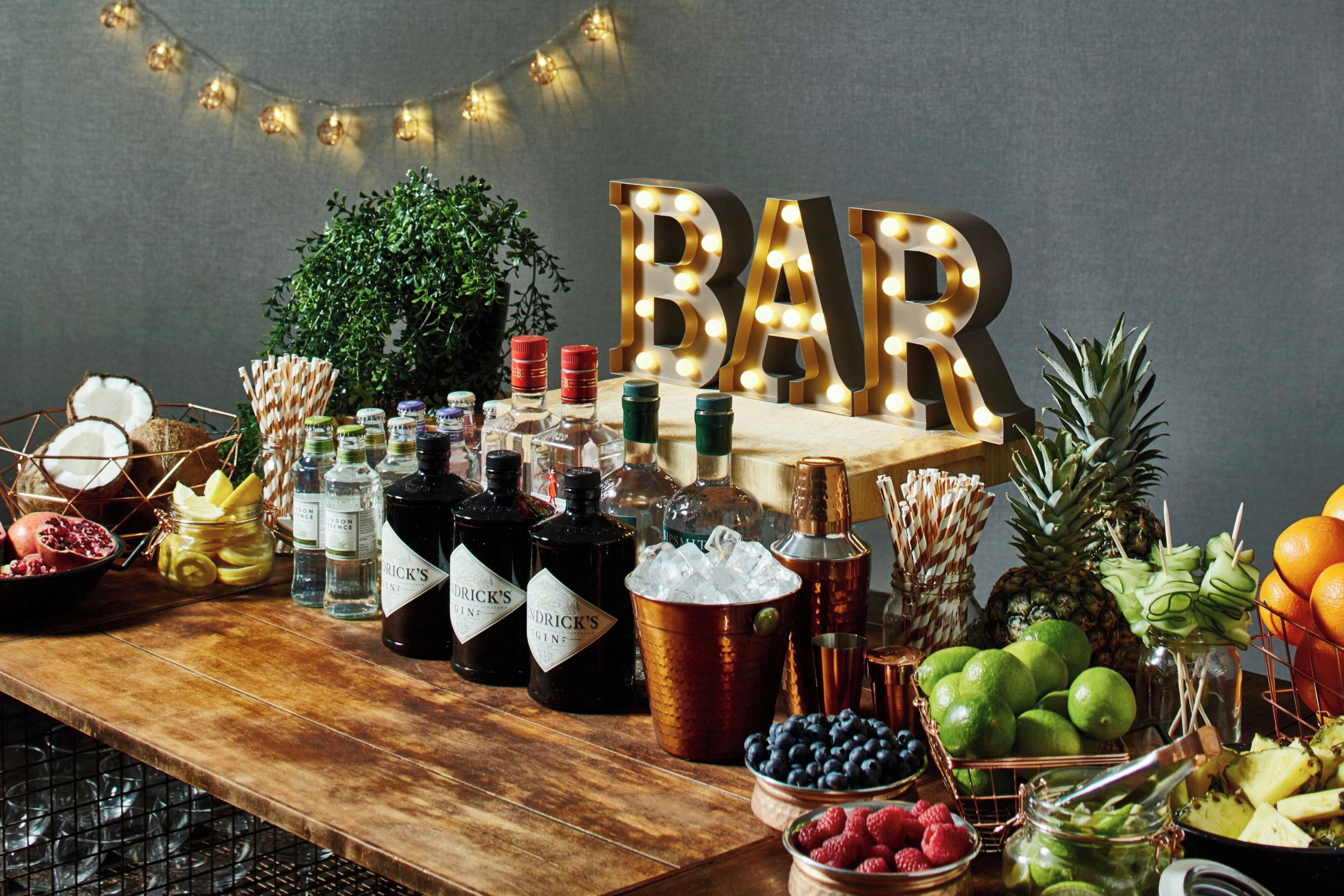 A bar setup with bottles, fruits, and a sign that reads 'BAR'.
