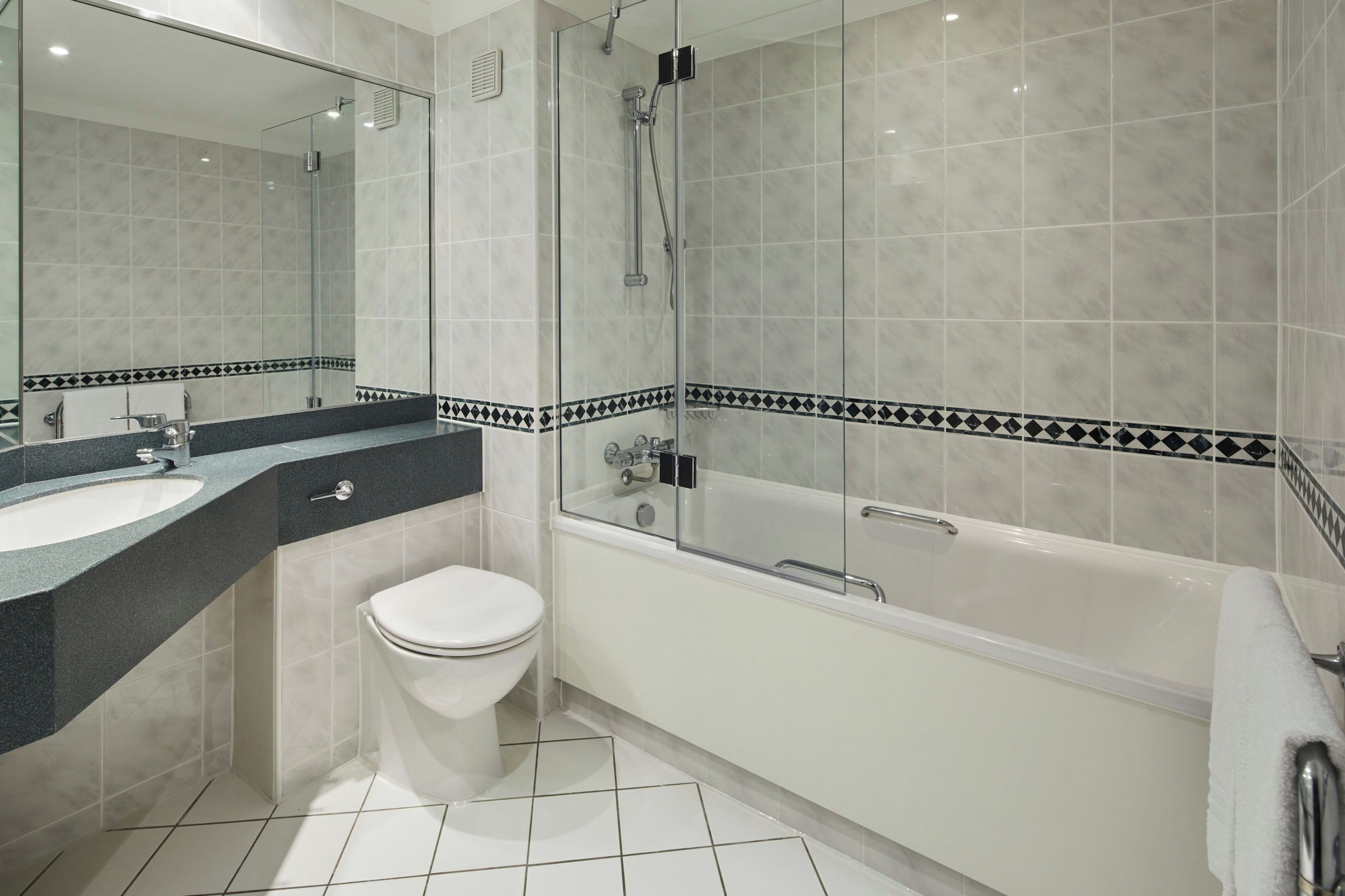 A modern bathroom with a glass-enclosed shower, a white toilet, and a bathtub.