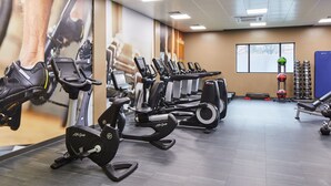 A gym with multiple cardio machines, weightlifting equipment, and a large mural on the wall. - Cardiff Marriott Hotel (Cardiff)