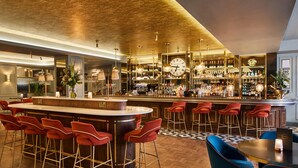 A bar area with a central bar, multiple stools, and a seating area with a table. - Cardiff Marriott Hotel (Cardiff)