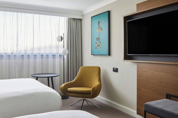 A hotel room with a bed, a chair, a small table, a TV, and a painting on the wall. - Cardiff Marriott Hotel (Cardiff)
