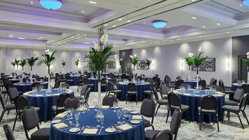 A conference room with round tables, chairs, and floral centerpieces.