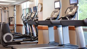 Une salle de sport équipée de tapis de course, de vélos elliptiques et d’appareils de musculation.