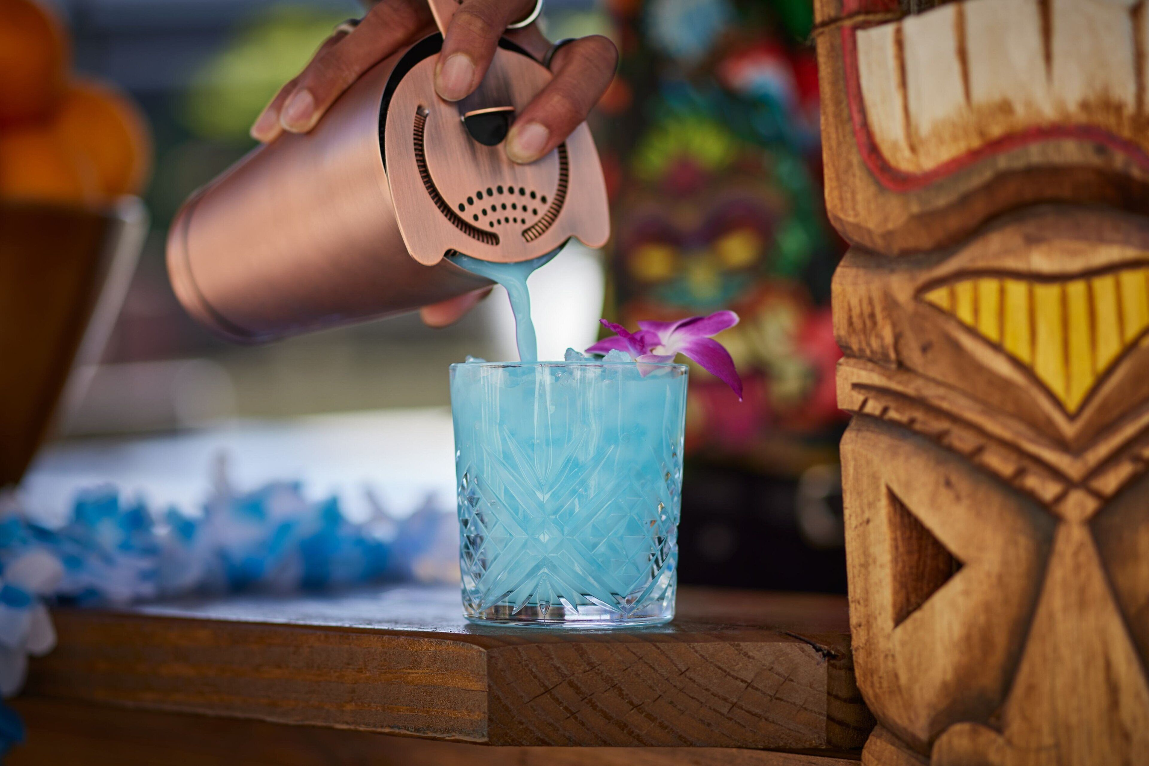 A hand pouring a blue liquid into a glass with a star pattern.