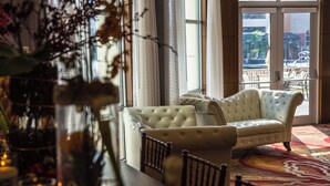 A plush sofa in a well-lit room with large windows, a patterned rug, and a small table with candles. - Gaithersburg Marriott Washingtonian Center (Gaithersburg)