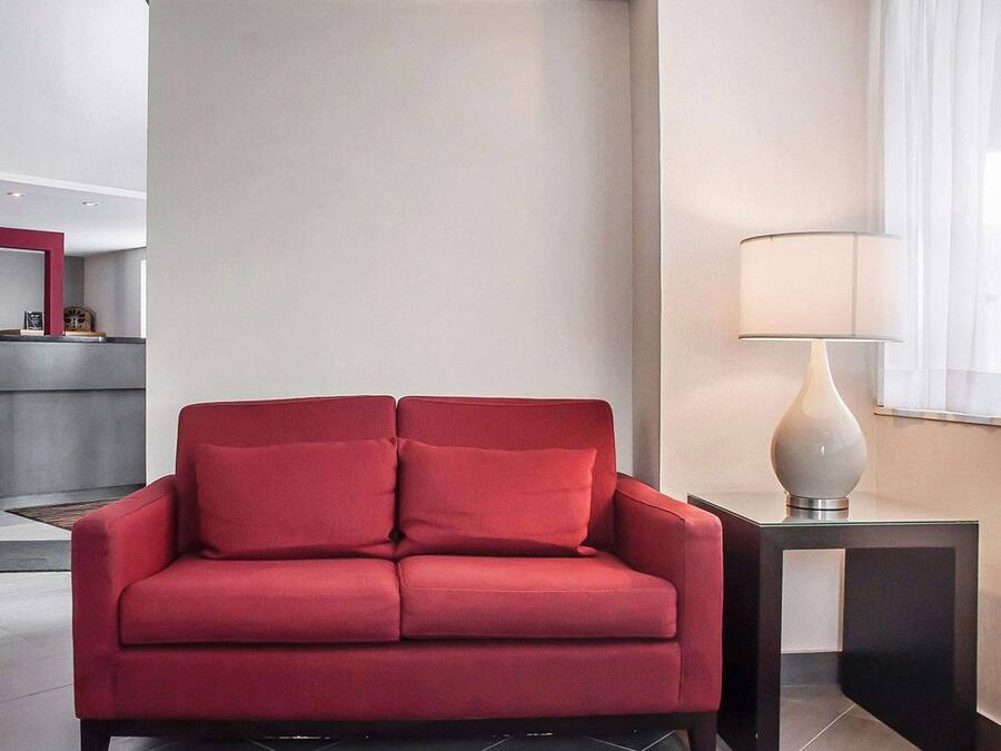 En rød sofa i en moderne stue med et sofabord og en lampe.