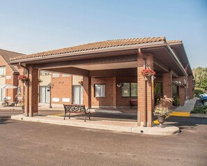 Ein Gebäude mit überdachter Terrasse, Backsteinwänden und einer Bank.