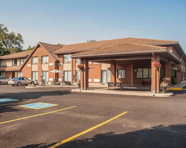 Ein Motel mit überdachtem Parkplatz, einer Bank und einer Terrasse mit Sitzgelegenheit.
