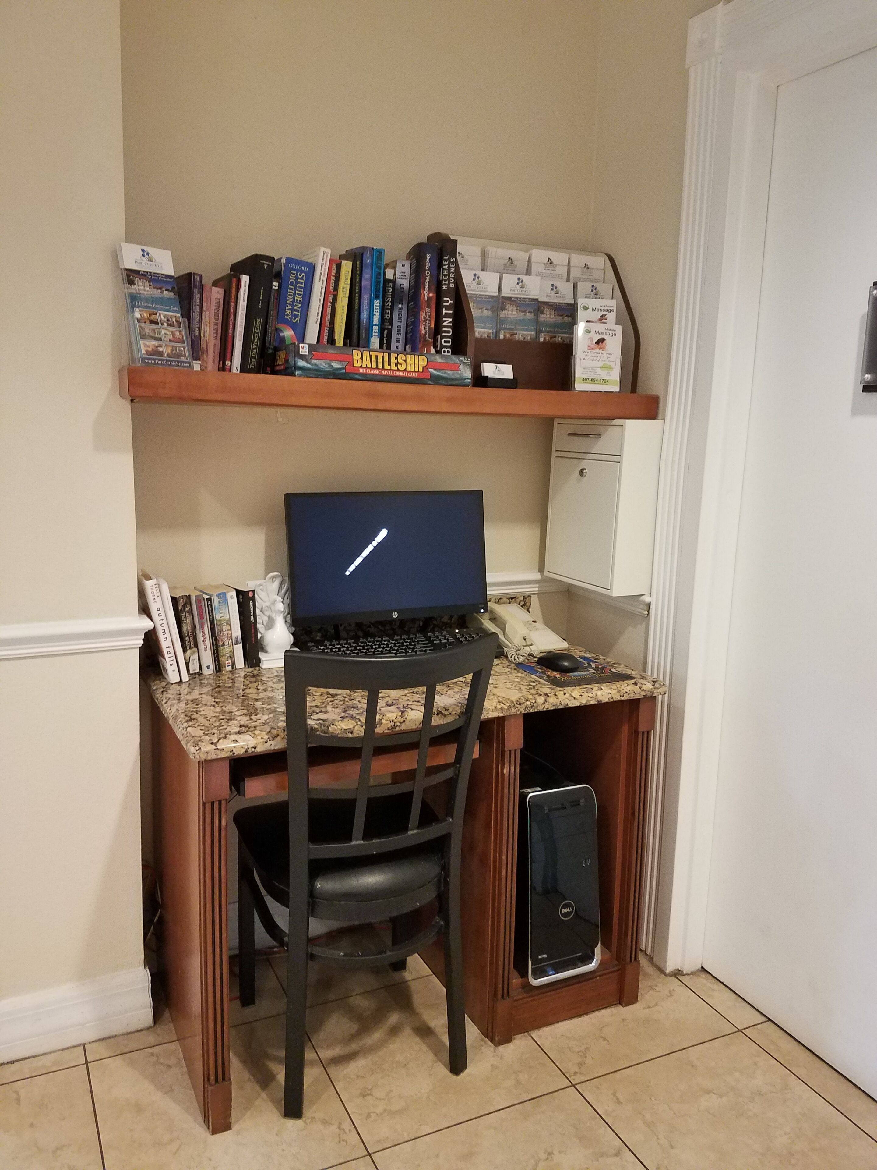 Un espace de travail aménagé à la maison, comprenant un bureau, une chaise, un ordinateur et des livres.