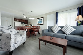 A multi-story building with balconies, surrounded by well-maintained lawns and flowering bushes. at Parc Corniche Condominium Suite Hotel