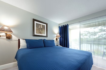 A swimming pool with lounge chairs and umbrellas, surrounded by palm trees and a multi-story building with balconies. at Parc Corniche Condominium Suite Hotel
