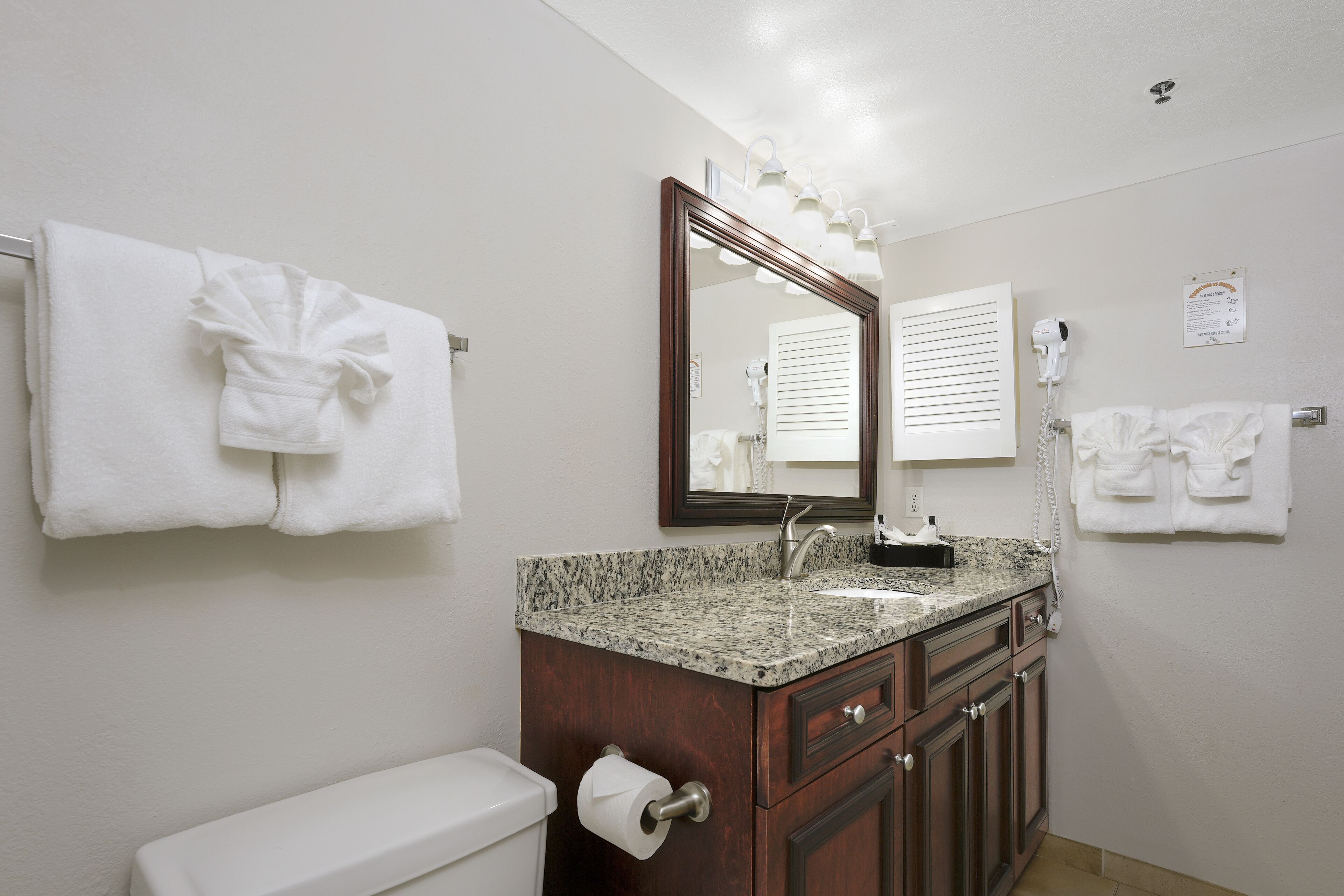 A bathroom with a toilet, sink, vanity, and towel rack.