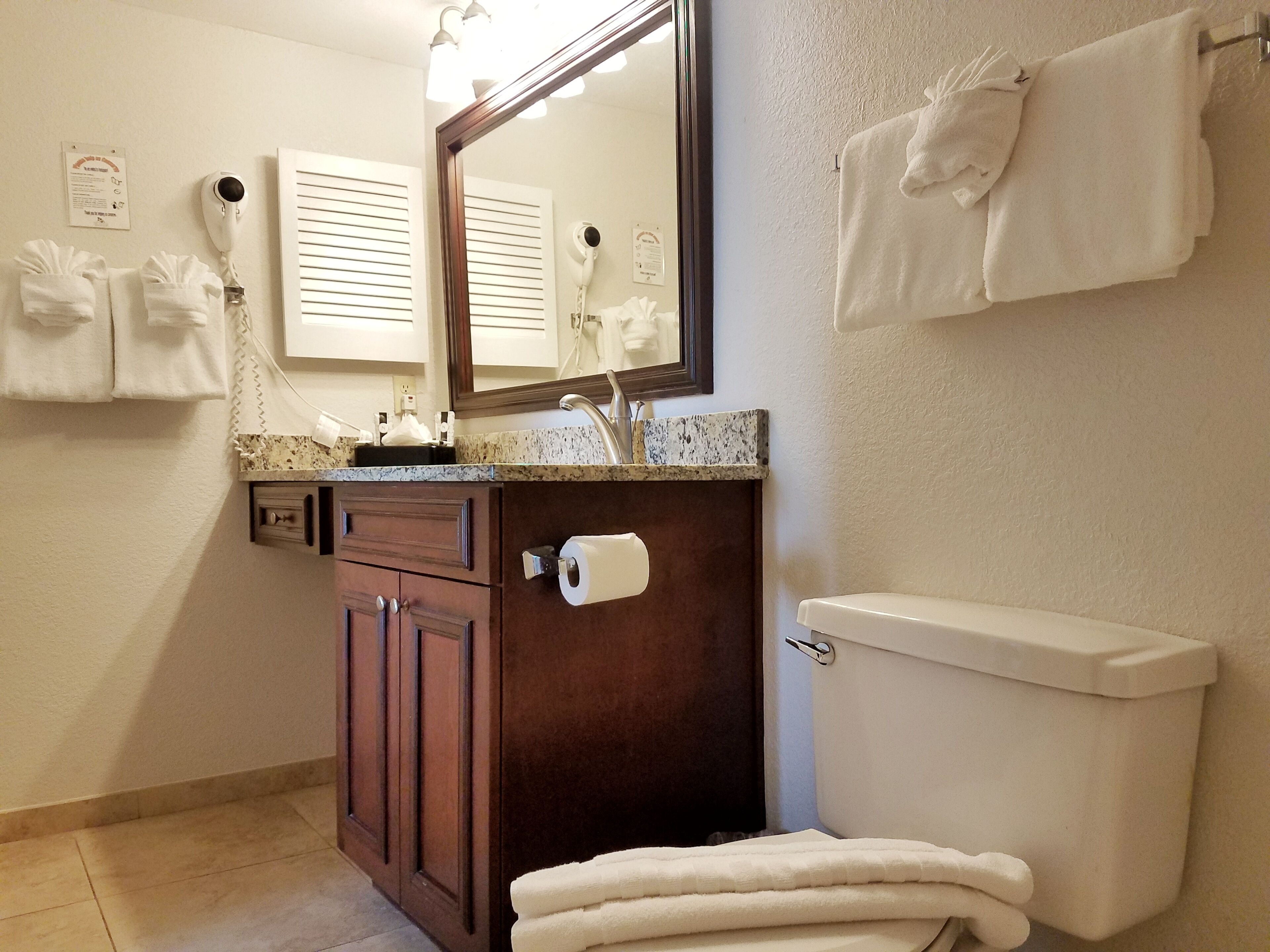 A bathroom with a toilet, a sink with a mirror, and a towel rack with towels.
