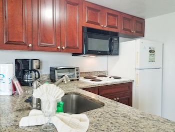 A multi-story hotel with balconies, a flat roof, and a well-maintained lawn. at Parc Corniche Condominium Suite Hotel