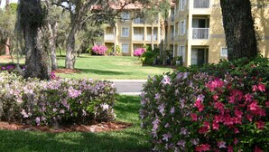 A multi-story building with balconies, surrounded by well-maintained lawns and flowering bushes. - Parc Corniche Condominium Suite Hotel (Orlando)