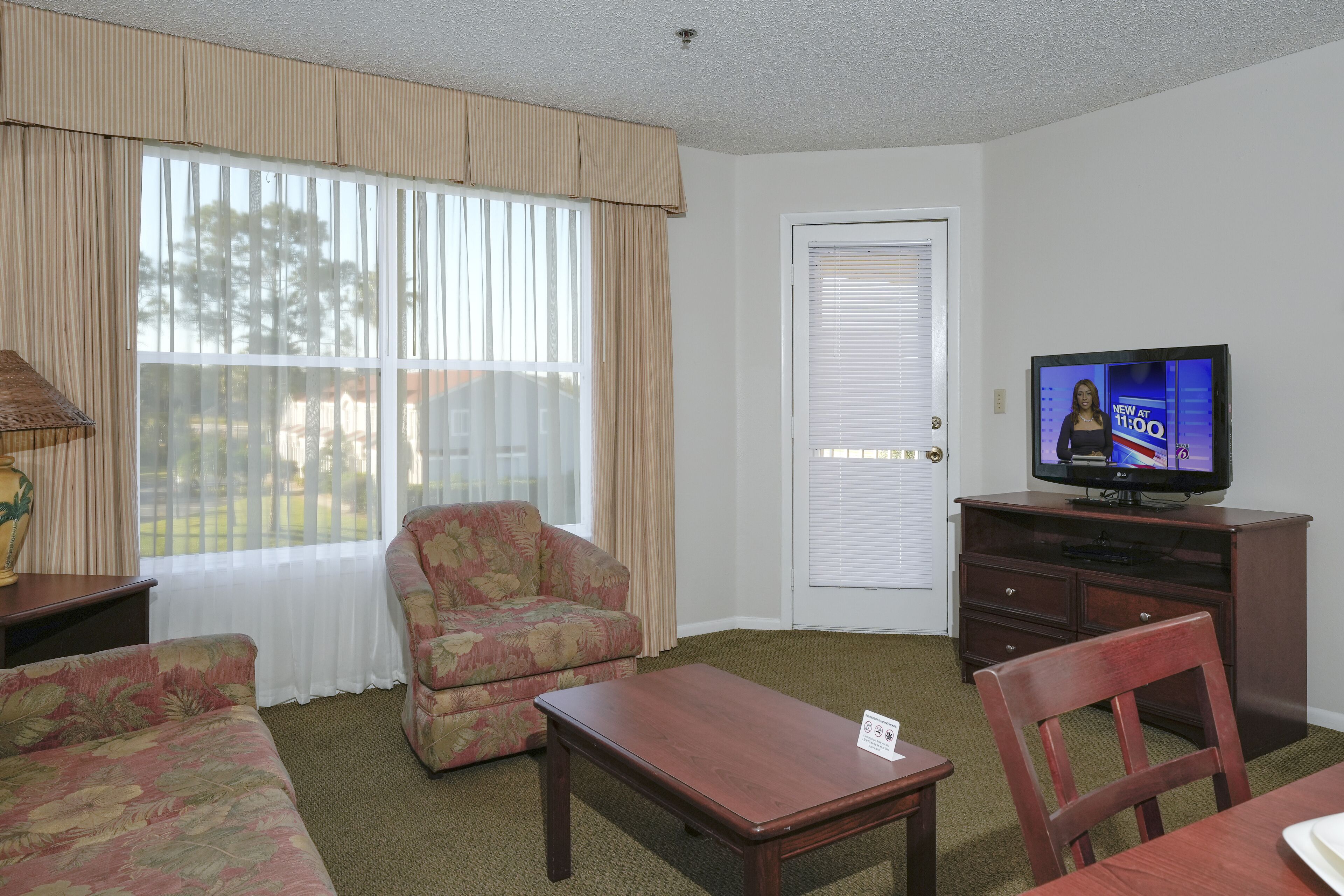 A living room with a sofa, armchair, coffee table, and a television on a stand.