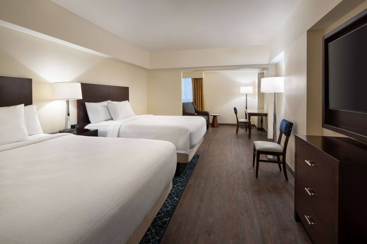 Een hotelkamer met twee bedden, een televisie, een bureau en een stoel.