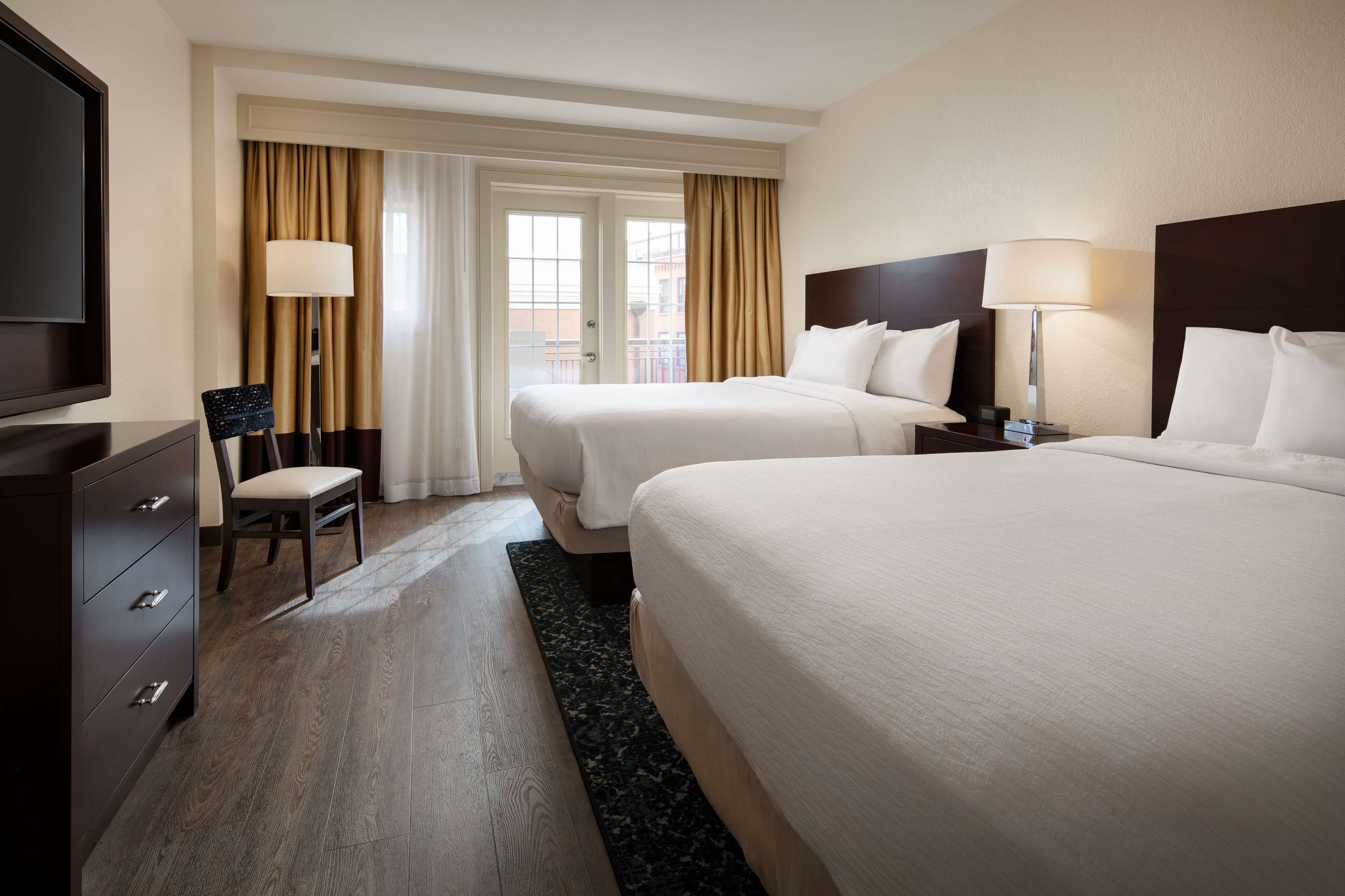 A hotel room with two beds, a TV, a desk, and a chair.