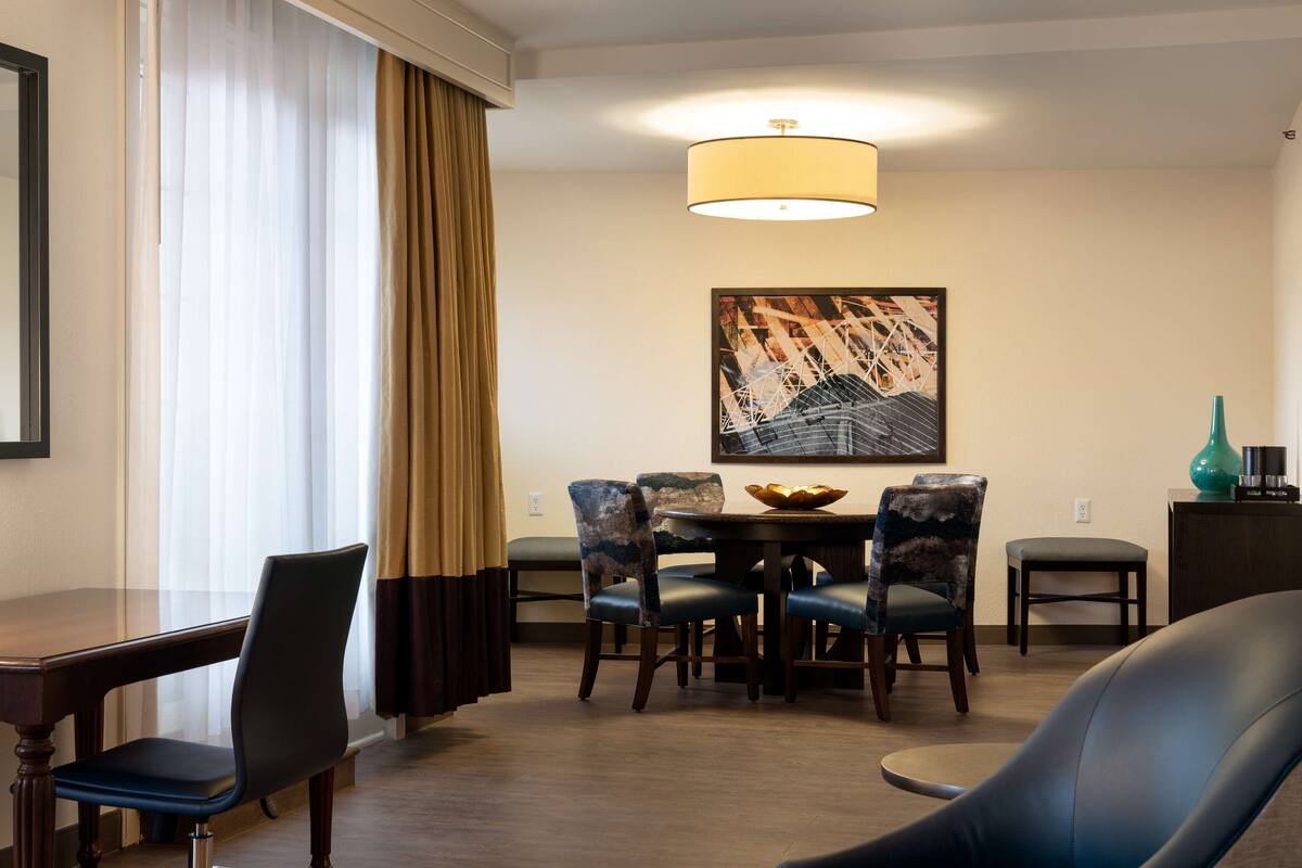 Een eetruimte met een ronde tafel, zes stoelen en een kroonluchter.