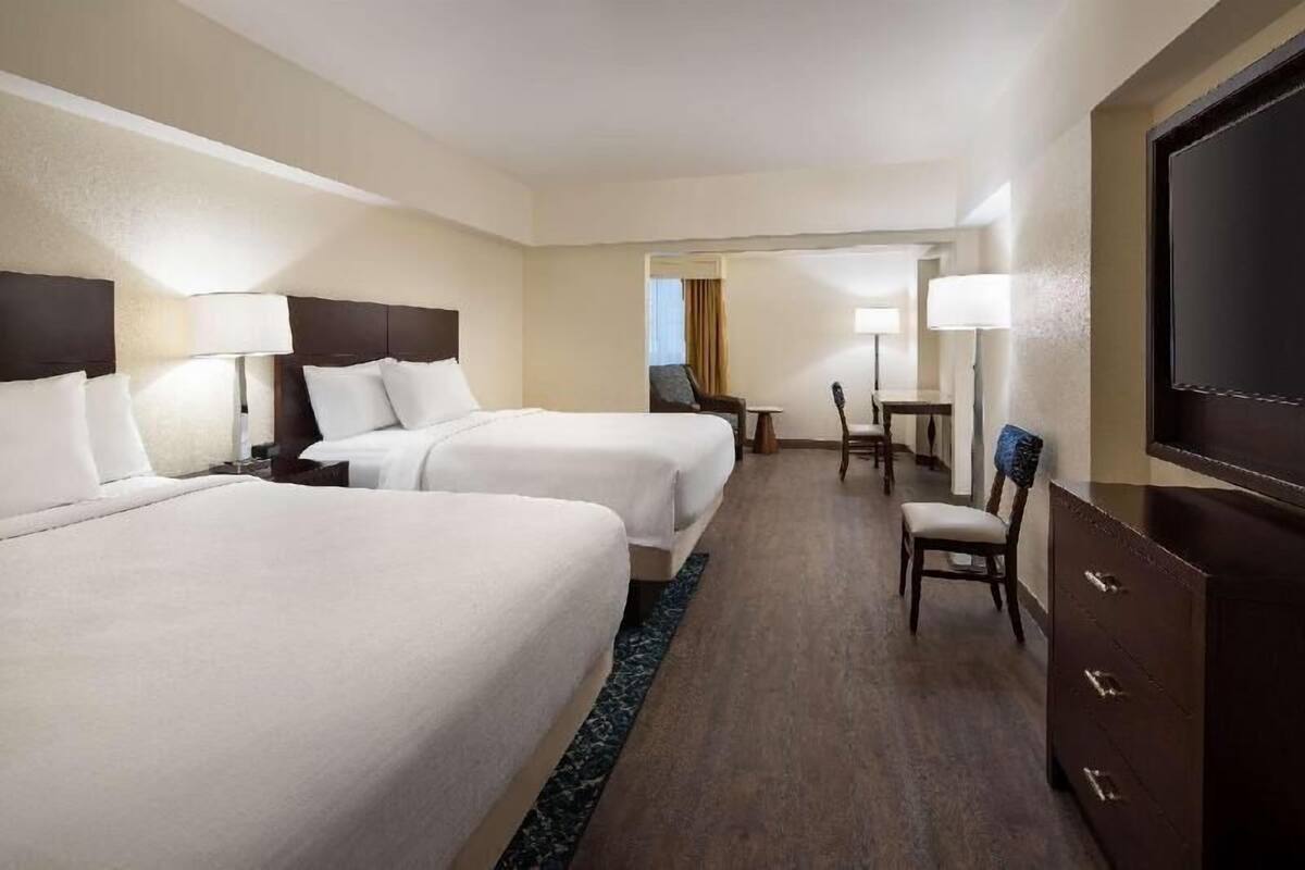 Een hotelkamer met twee bedden, een bureau, een stoel, een televisie en een dressoir.