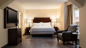 A hotel room with a large bed, a TV, a desk with a lamp, and a chair. - Embassy Suites by Hilton New Orleans (New Orleans)
