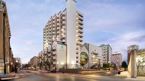 A modern hotel with a unique architectural design, featuring a prominent vertical tower and a circular glass facade. - Embassy Suites by Hilton New Orleans (New Orleans)
