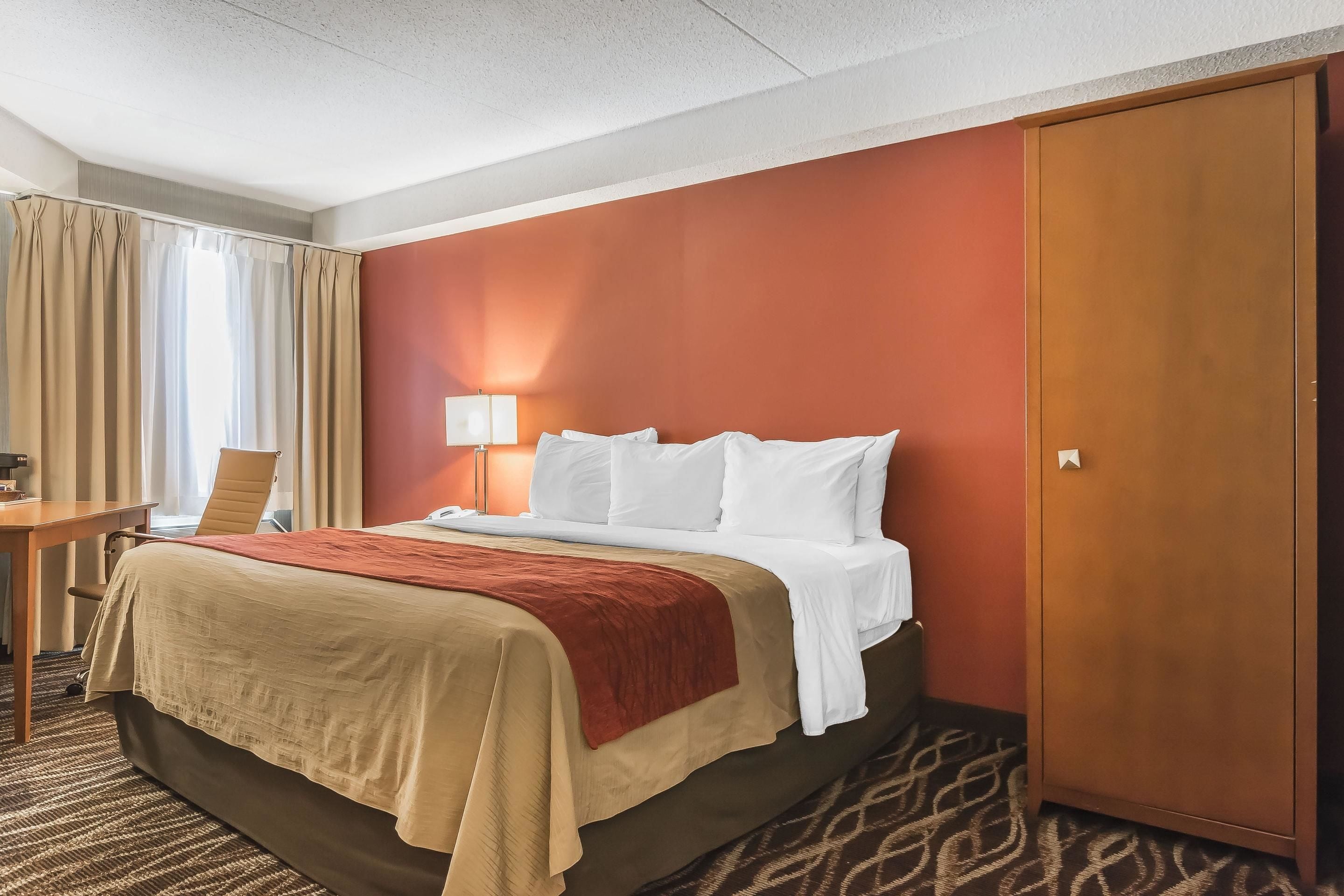 Ein Hotelzimmer mit einem Bett, einem Schreibtisch, einem Sessel, einem Kleiderschrank und einer Lampe.