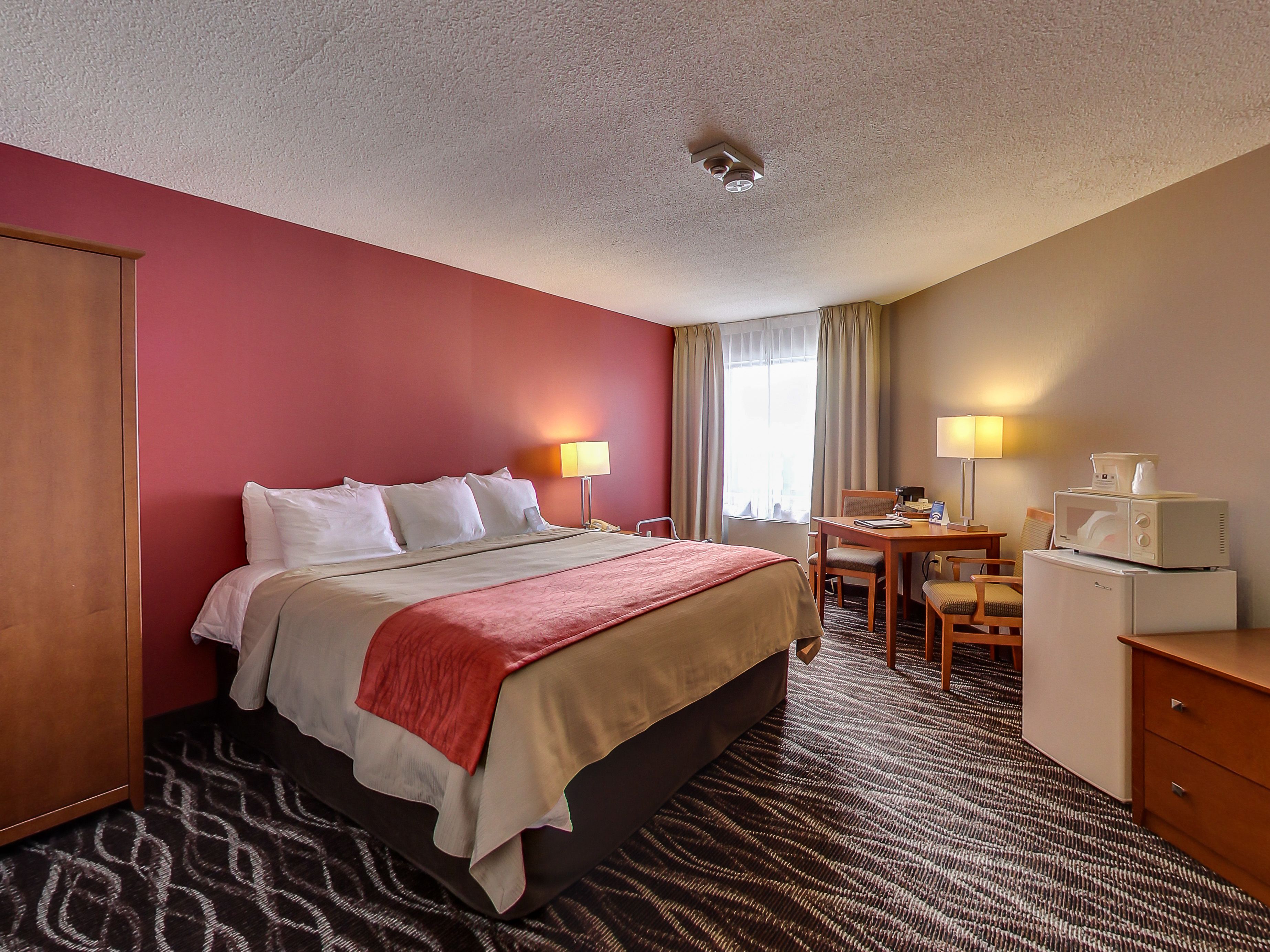 Habitación de hotel con cama, escritorio, silla y microondas.