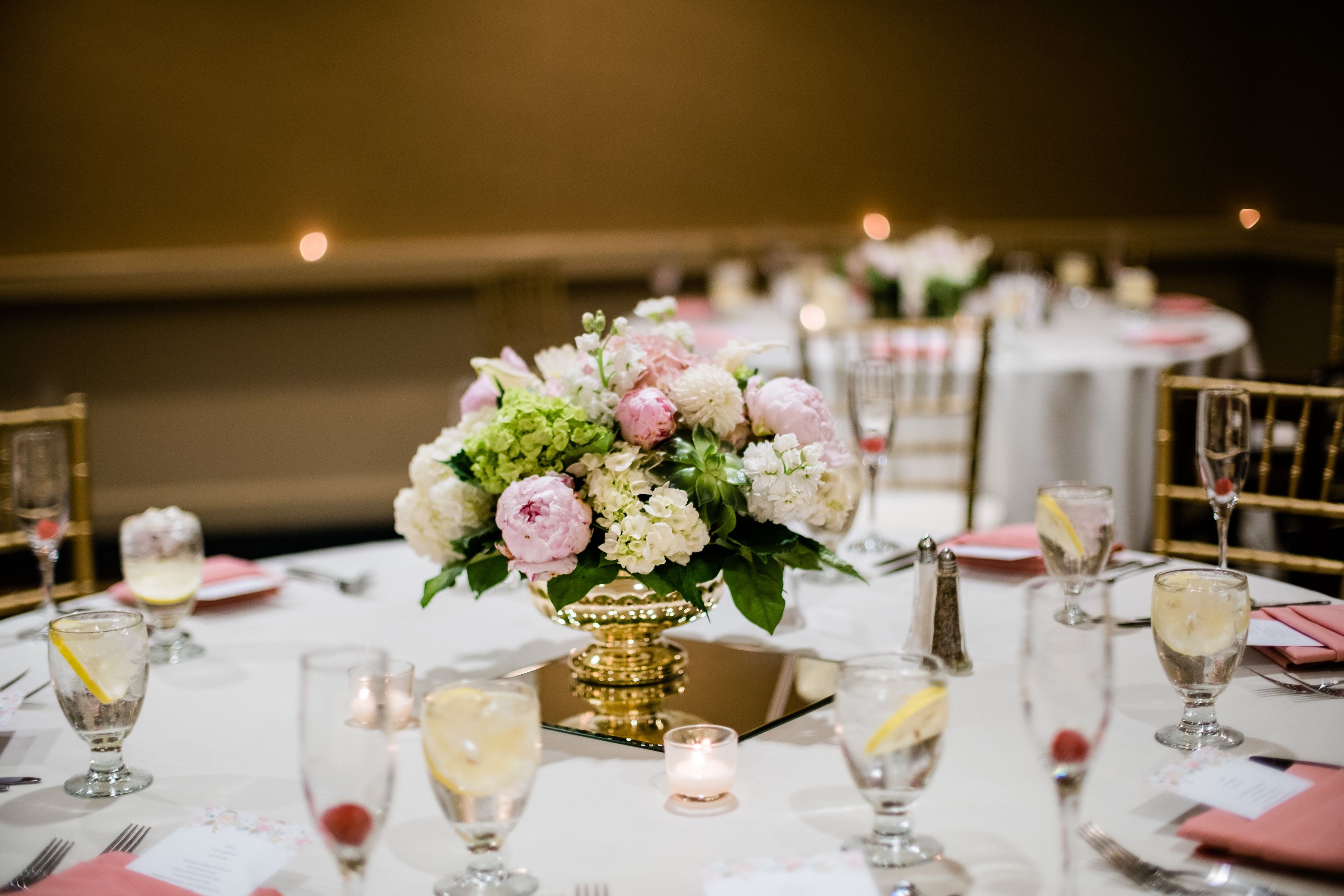 A table set for a formal event with a centerpiece of flowers, glasses of champagne, and candles.