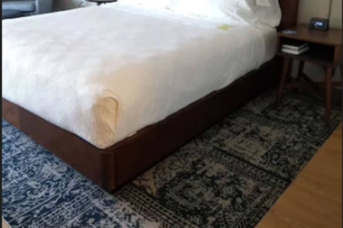 Ein Hotelzimmer mit einem großen Bett, einem Sessel, einem Nachttisch und einer Wand mit gerahmten Bildern.