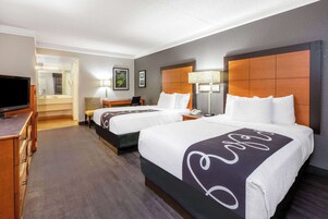 Una habitación de hotel con dos camas, televisión, escritorio y una silla.
