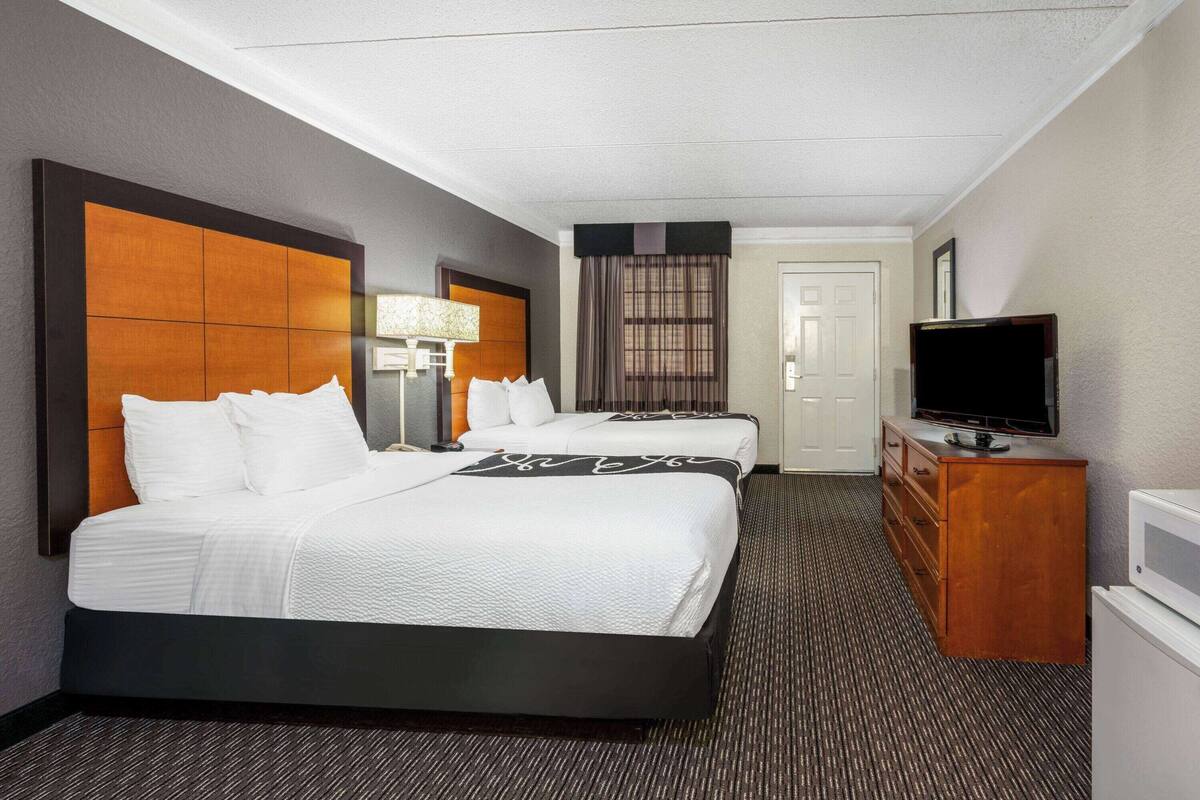 Ein Hotelzimmer mit einem großen Bett, einem Schminktisch, einem Fernseher und einer Tür.