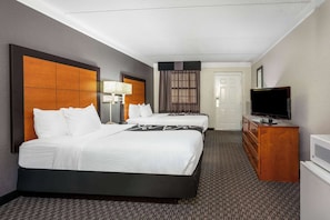 A hotel room with a large bed, a dresser, a television, and a door. - Super 8 by Wyndham The Woodlands North (Shenandoah)