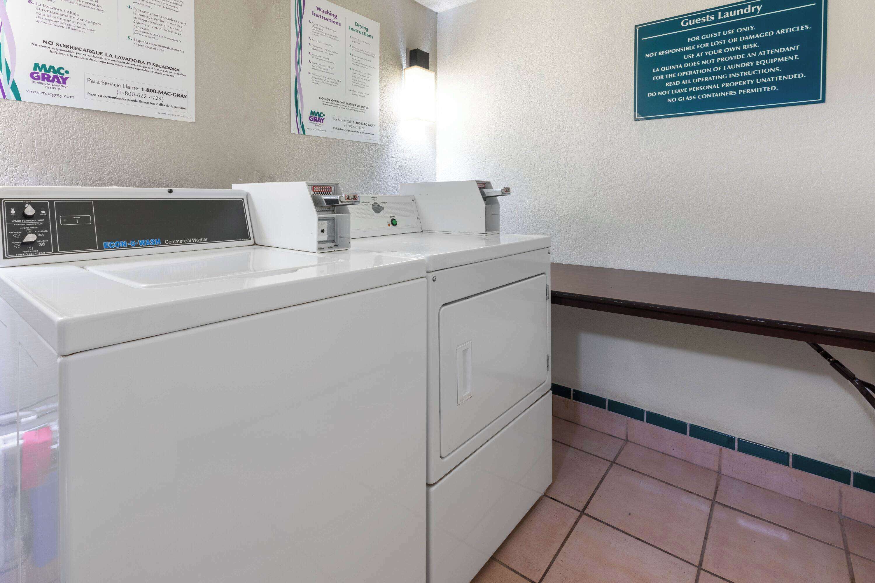A laundry area with a commercial washer and dryer, a sink, and a sign indicating it's for guest use only.