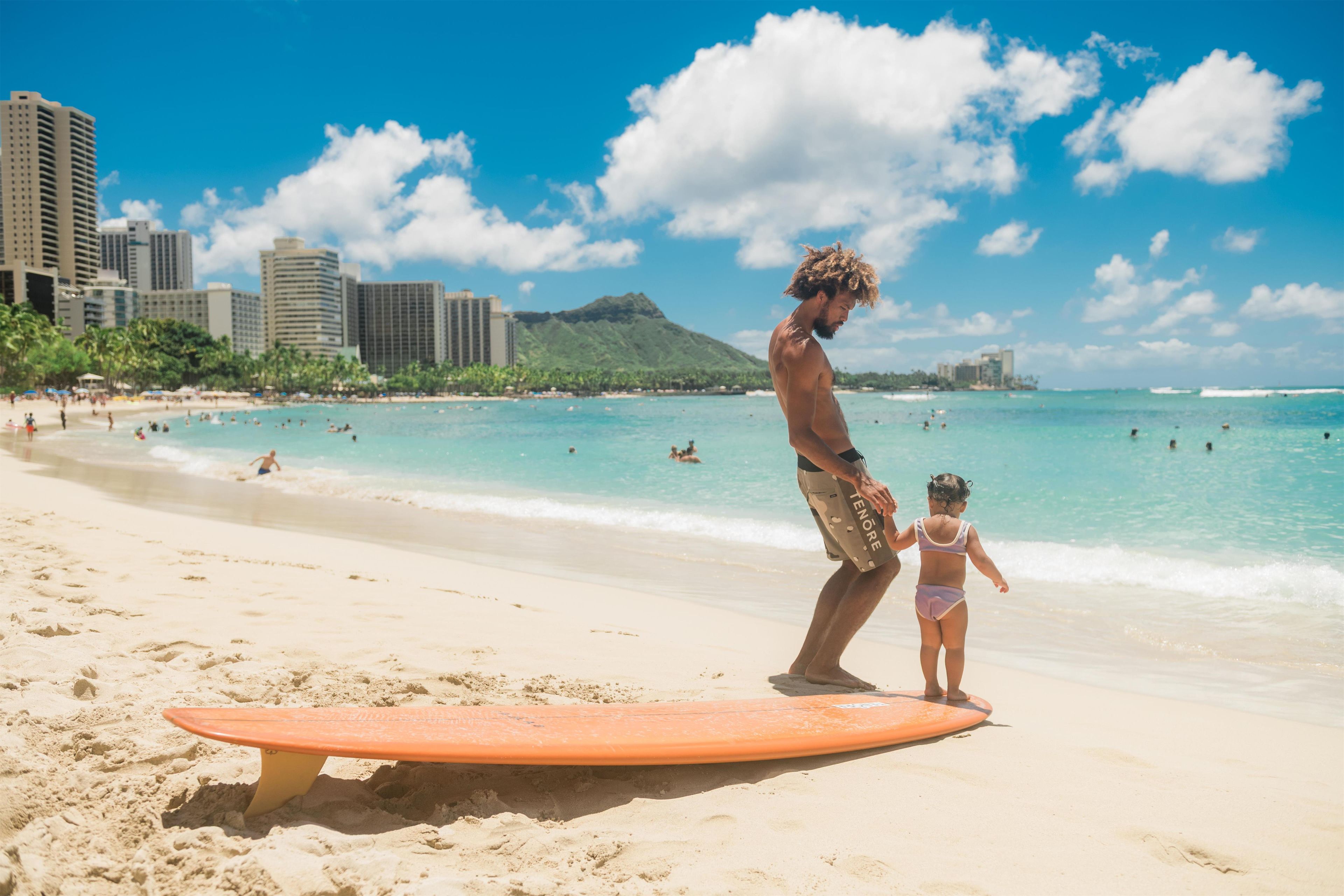 A beach scene with a surfboard, a person, and a child.