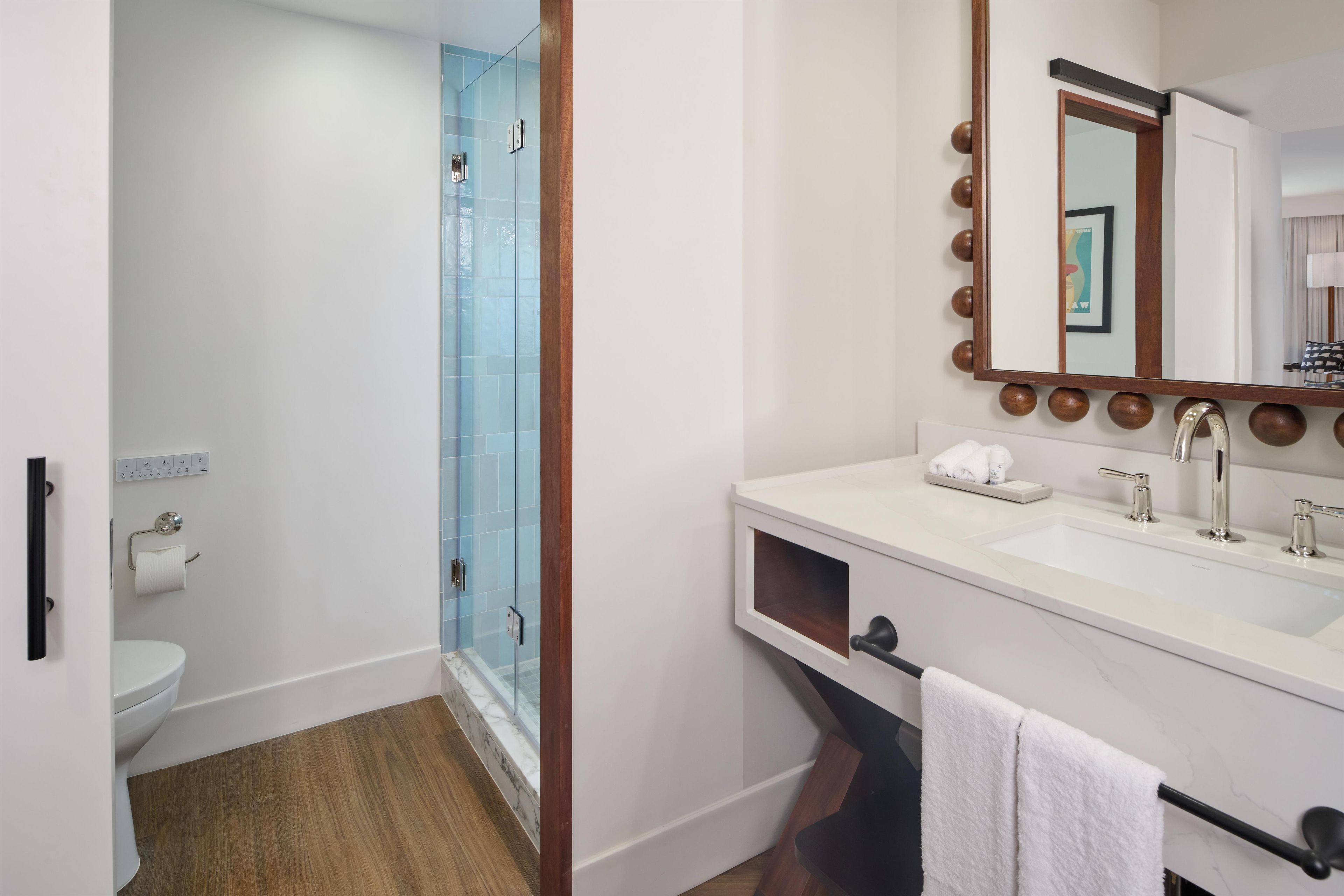 A bathroom with a glass shower enclosure, a white sink with a mirror, and a towel rack.